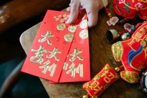 High angle of crop anonymous female with envelopes placed on wooden table for traditional New Year celebration